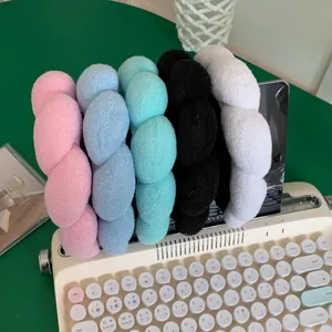 Thick braided plush headbands in pink, blue, green, black and white displayed on a typewriter