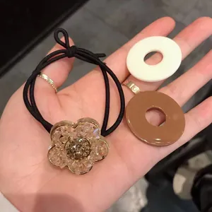 Detail of elastic hair tie with crystal floral charm and resin ring accessories