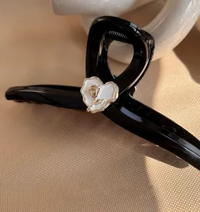 Macro detail of French style black hair claw clip featuring a golden rose heart motif