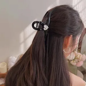 Elegant black hair claw clip with white camellia flower on a woman's bun hairstyle