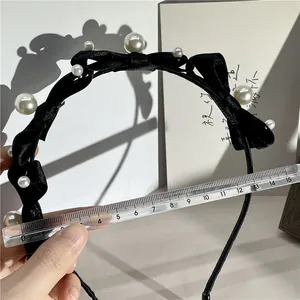 Detail shot showing a 12.5cm diameter measurement of the black bow and pearl headband