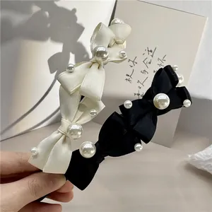 Detail shot of elegant bow headbands with faux pearls in creamy white and black finish