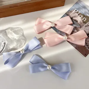 Detailansicht von Schleifen-Haarspangen aus Satin in Rosa und Blau mit Perlenverzierung