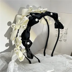 Close-up of pearl bow headbands in black and cream silk with handmade labels