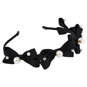 Elegant black bow headband with white pearls and ribbed fabric texture on white background
