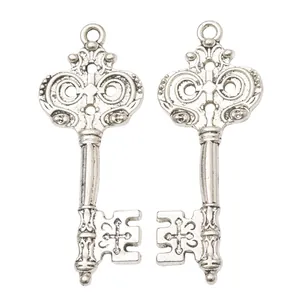 Two vintage antique silver zinc alloy key charms with intricate symmetrical scroll embossing