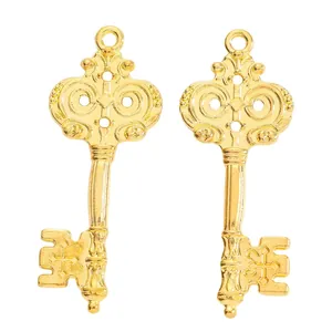 Pair of vintage gold zinc alloy key pendants with ornate scrollwork on white background