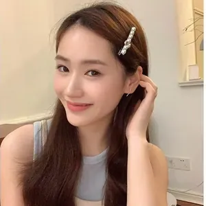 Silver hair clip with white pearls worn by a model in a minimalist indoor setting