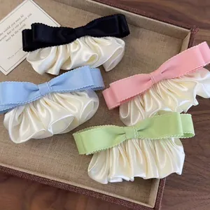 Détail de quatre chouchous nœuds en satin de couleurs variées sur un plateau