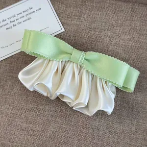 Barrette à nœud vert clair avec texture plissée en soie sur fond sombre élégant