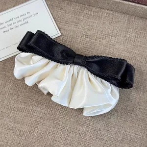 Détail de la pince à cheveux noeud noir et blanc avec texture satinée sur tissu