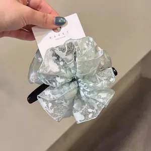 Gros plan sur le chouchou géant en dentelle d'organza vert clair aux motifs floraux