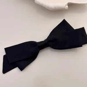 Detailed top view of a large black matte double-layered bow hair clip on a soft white surface