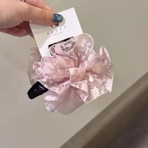 Détail d'un chouchou en dentelle rose avec motifs floraux et étiquette de marque
