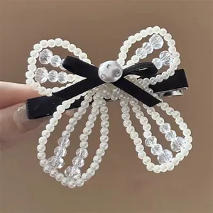Close-up of pearl bow hair clip with black velvet ribbon and sparkling beads detail