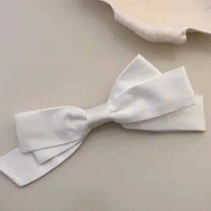 Elegant large white satin bow hair clip with a smooth silky finish on a minimal background