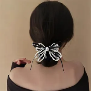 Elegant pearl bow hair clip with black ribbon accent shown on model's hair