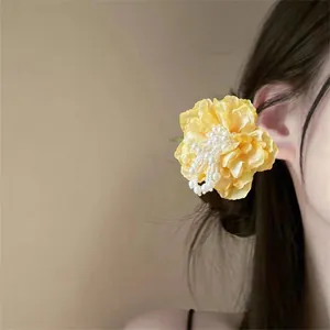 Ethereal yellow fabric camellia hair clip with pearl tassels on a woman's profile
