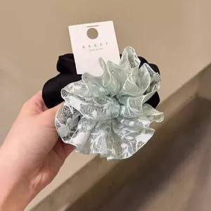 Détail d'un chouchou géant multicouche en dentelle florale et satin soyeux