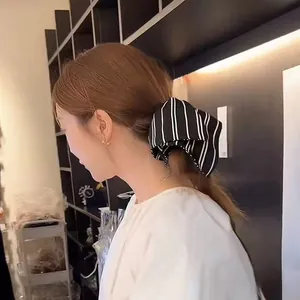 Chouchou géant en satin à rayures noires et blanches présenté sur une coiffure en queue de cheval