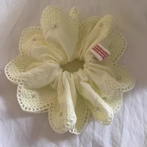 Detail van kanten scrunchie met parels en handgemaakt label op witte stof