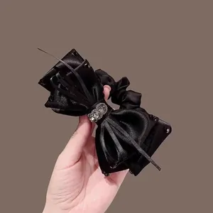 Coletero elegante de satén negro con lazo grande y adornos de pedrería brillante