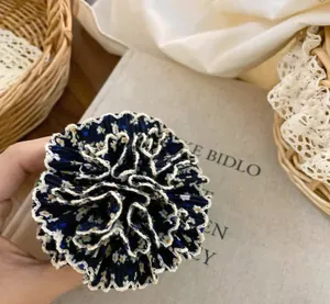 Primer plano de una pinza para el pelo tipo hortensia plisada con flores y encaje