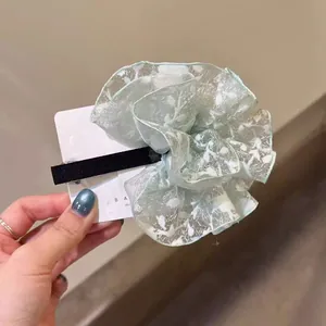 Détail du chouchou en organza vert menthe avec broderie florale de feuilles blanches