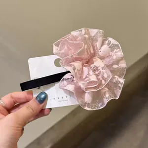 Gros plan d'une pince à cheveux fleur en dentelle rose brodée sur présentoir