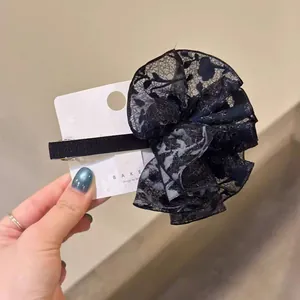 Vue détaillée d'une grande pince à cheveux en dentelle noire sur carte de support