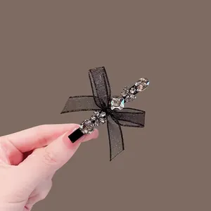 Macro shot of black mesh bow hair clip with sparkling rhinestones on brown background