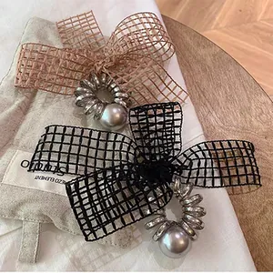 Detail of spiral hair ties with fabric bows and large faux pearls on a wooden desk