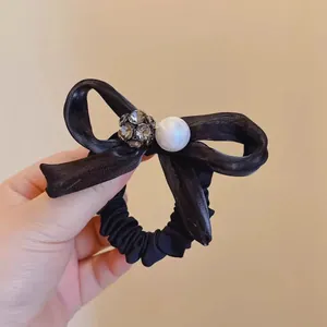 Detail of black silk hair scrunchie with sparkling rhinestone ball and pearl accent