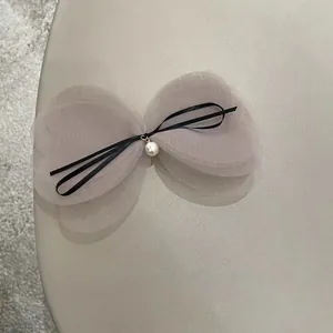 Detailed view of layered pink mesh bow hair clip with black ribbon and white pearl accent