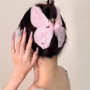 Pince à cheveux papillon rose avec ailes en gaze et strass sur la coiffure
