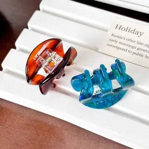 Elegant oval tortoiseshell and marble acetate hair clips on a white display stand