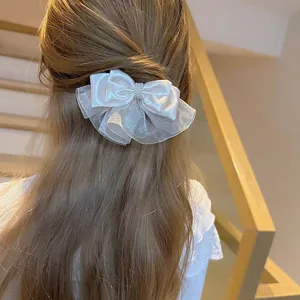 Elegant white organza bow hair clip with pearls shown on model in a soft indoor setting