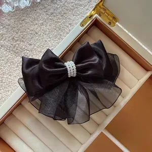 Macro detail of black organza bow hair clip featuring elegant triple-row pearl embellishments