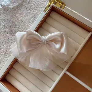 Detail of champagne organza layers and center pearls on elegant hair clip