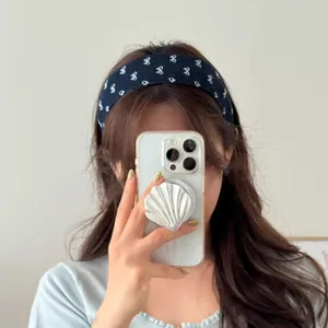 Diadema de tela vaquera azul con estampado floral y soporte para móvil con forma de concha