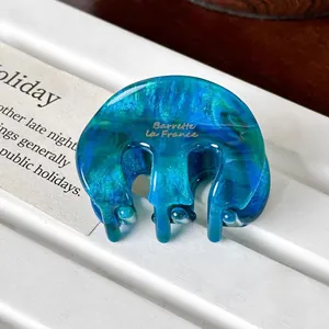 Close-up of blue-green marble texture acetate hair claw clip with golden text detail