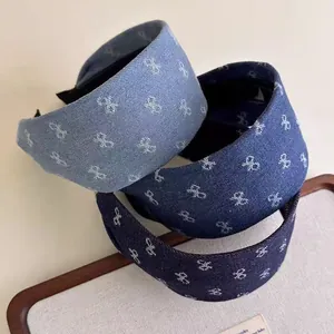 Close-up of three blue denim headbands with small bow embroidery and soft padding