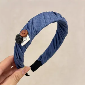 Close-up of blue twill fabric headband featuring wood buttons and Hand Made label
