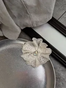 Detail of white lace hair claw with rhinestones in a silver tray for summer styling