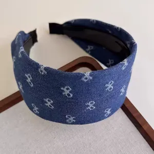 Detail of wide blue denim headband featuring white bow print and textured fabric