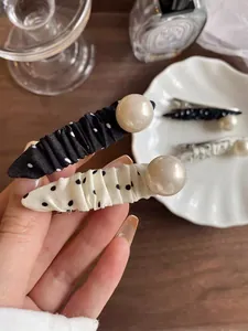 Detail of polka dot fabric hair clips with large pearl accent in black and white