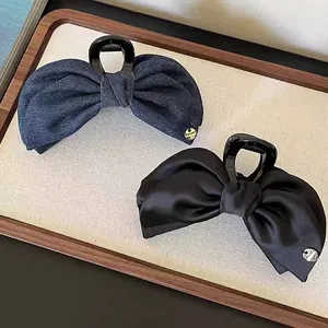 Denim and satin bow claw clips for women featuring golden charm detail on a display tray