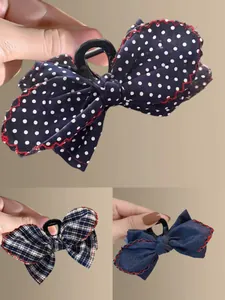 Detailed close-up of three bow hair claws featuring denim patterns and red wavy stitching