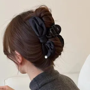 Elegant black satin bow hair claw clip shown on a hairstyle for women fashion