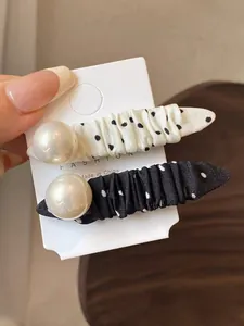 Detail view of retro polka dot fabric hair clips with elegant large white pearls